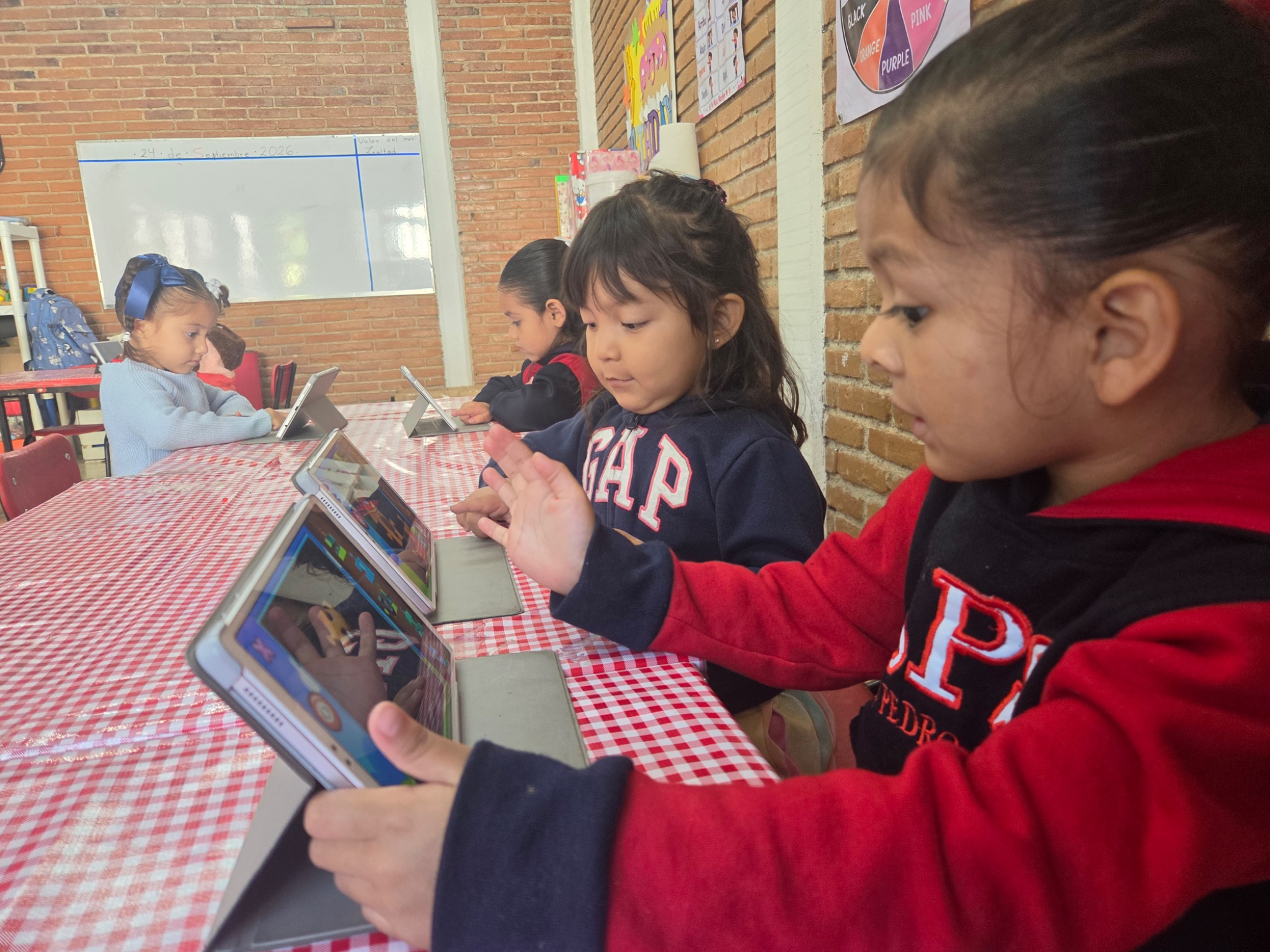 Alumnos pequeños desarrollando pensamiento lógico con tablets